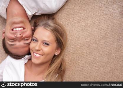 Portrait of a young couple lying on the floor with their heads close to each other