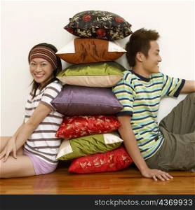 Portrait of a young couple sitting and leaning against a stack of cushions