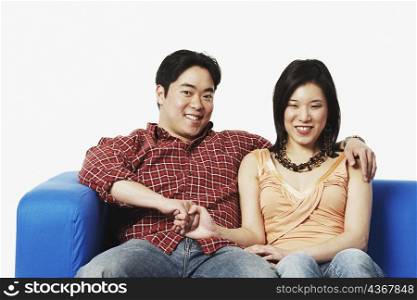 Portrait of a young couple sitting on a couch holding hands