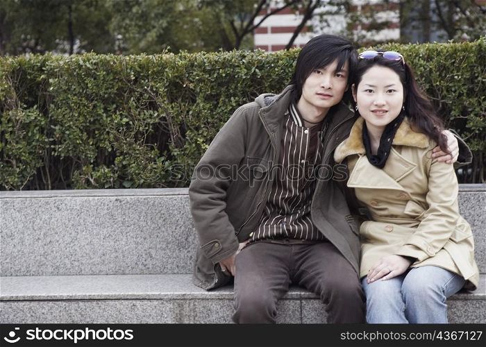 Portrait of a young couple sitting on a ledge