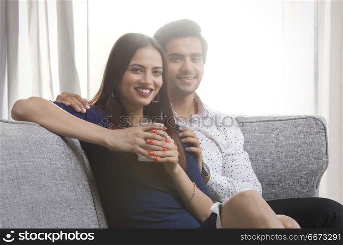 Portrait of a young couple sitting on sofa