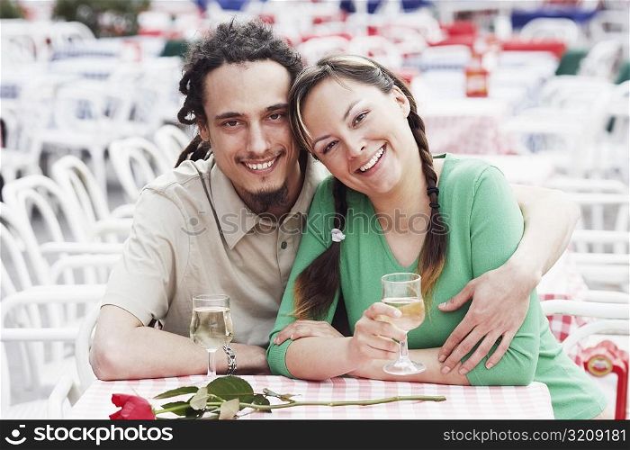 Portrait of a young couple sitting together at a sidewalk cafe