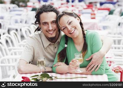 Portrait of a young couple sitting together at a sidewalk cafe