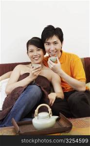 Portrait of a young couple smiling and sitting on a couch
