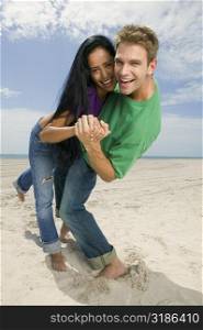 Portrait of a young couple smiling and standing on the beach