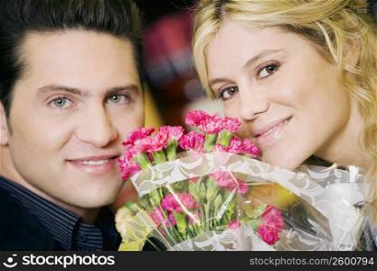 Portrait of a young couple smiling with a bouquet of flowers