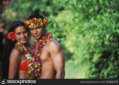 Portrait of a young couple standing together wearing garlands, Hawaii, USA