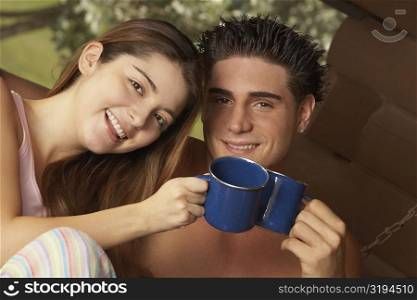 Portrait of a young couple toasting cups of tea and smiling