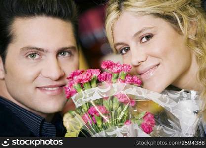 Portrait of a young couple with a bouquet of flowers between them