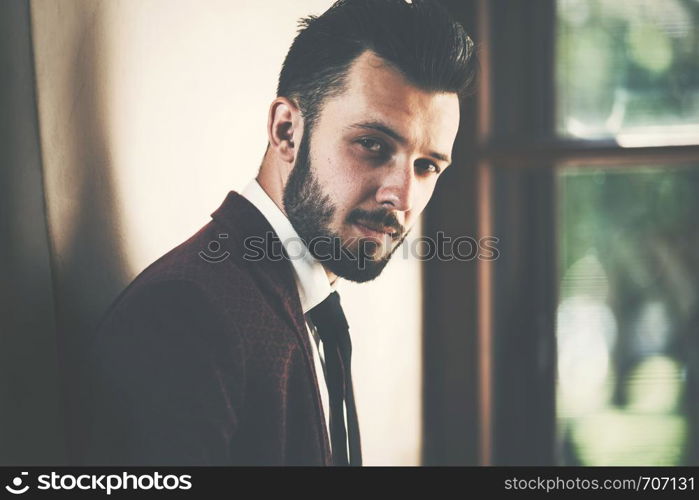 Portrait of a young fashionable man by the window (vintage effect)