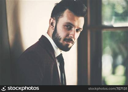 Portrait of a young fashionable man by the window (vintage effect)