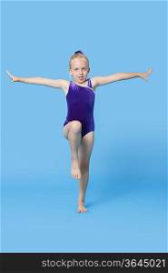 Portrait of a young female gymnast performing over blue background