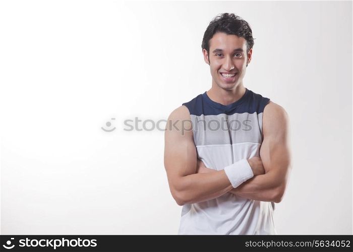 Portrait of a young fit man with arms crossed over white background