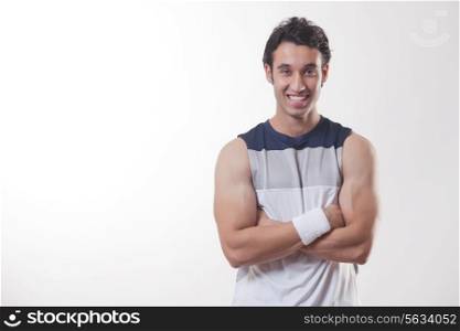 Portrait of a young fit man with arms crossed over white background