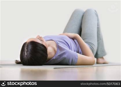 Portrait of a young fitness woman lying on a yoga mat and exercising