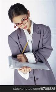Portrait of a young girl dressed as a businesswoman writing on a clipboard