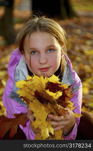 Portrait of a young girl holding autumn leaves