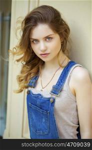 Portrait of a young girl in denim overalls, close up