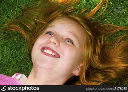 Portrait of a young girl relaxing on green grass outside