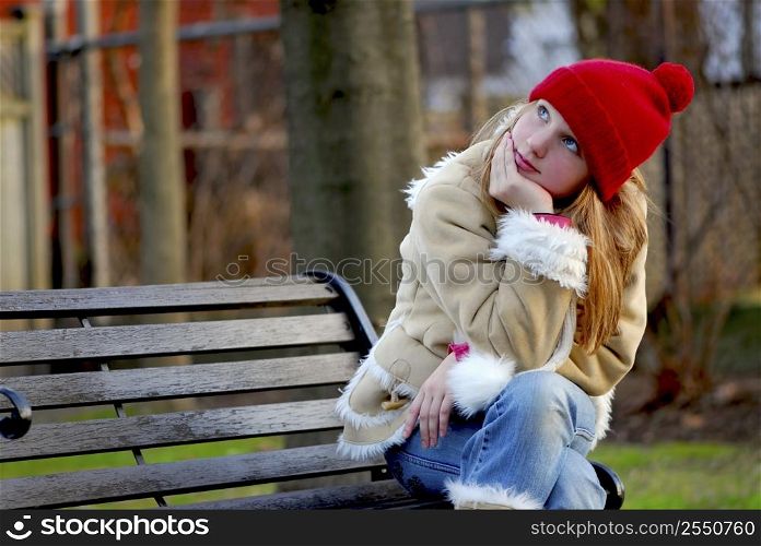 Portrait of a young girl sitting on a bench outside