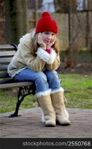 Portrait of a young girl sitting on a bench outside