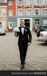 portrait of a young guy groom in a black suit on a rainy day