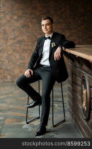 portrait of a young guy groom in a black suit on a rainy day