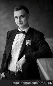 portrait of a young guy groom in a black suit on a rainy day