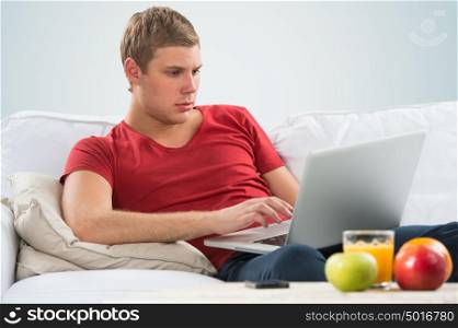 Portrait of a young guy using laptop at home