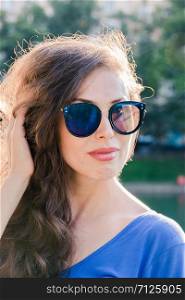 Portrait of a young handsome girl in sunglasses with dark hair. Close up sunny portrait.