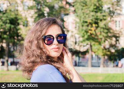 Portrait of a young handsome girl in sunglasses with dark hair. Close up sunny portrait.