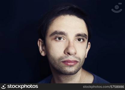 portrait of a young handsome man in a blue shirt on a black background close up