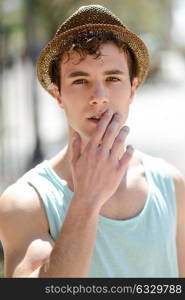 Portrait of a young handsome man, model of fashion, wearing a sun hat in urban background