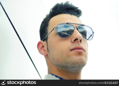 Portrait of a young handsome man, model of fashion, wearing tinted sunglasses