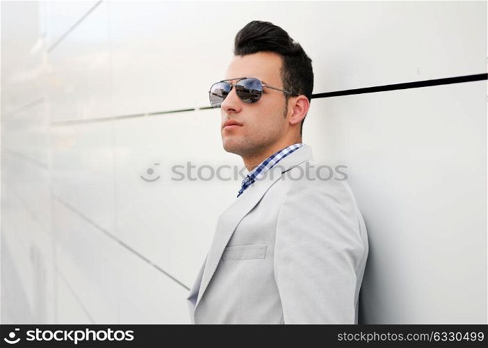 Portrait of a young handsome man, model of fashion, wearing tinted sunglasses