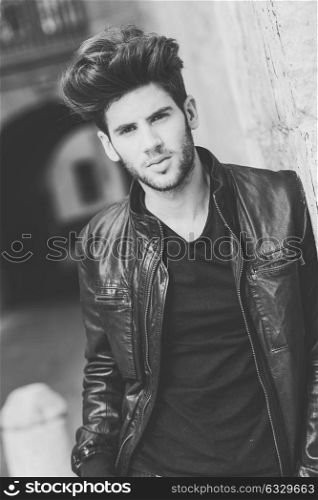 Portrait of a young handsome man, model of fashion, with modern hairstyle in urban background wearing and leather jacket