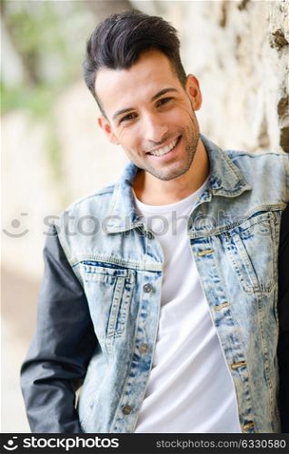 Portrait of a young handsome man, model of fashion, with modern hairstyle smiling in urban background