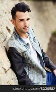 Portrait of a young handsome man, model of fashion, with modern hairstyle smiling in urban background