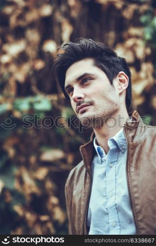 Portrait of a young handsome man, model of fashion, with modern hairstyle in urban background, wearing casual clothes.