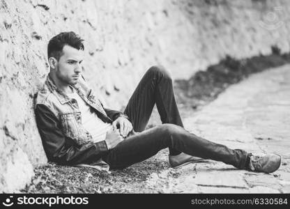 Portrait of a young handsome man, model of fashion, with modern hairstyle in urban background