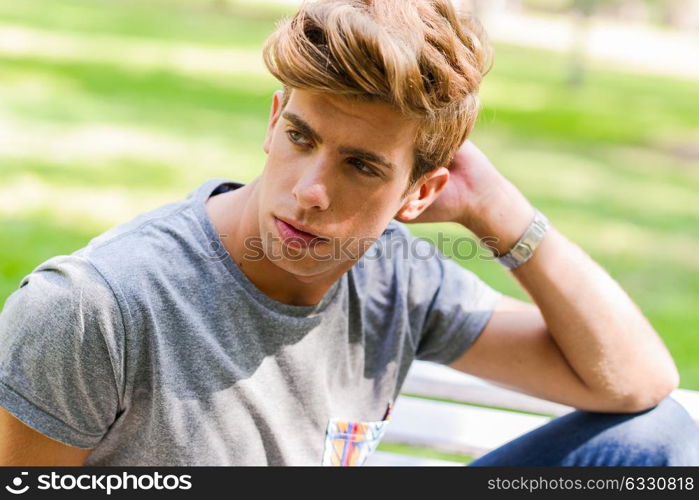 Portrait of a young handsome man, model of fashion, with modern hairstyle in urban background. Blonde hair