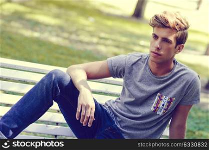 Portrait of a young handsome man, model of fashion, with modern hairstyle in urban background. Blonde hair