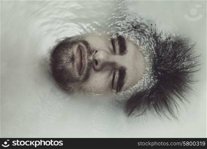 Portrait of a young handsome man taking a bath