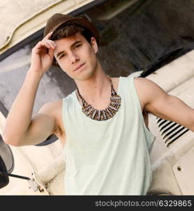 Portrait of a young handsome man with an old van wearing a sun hat