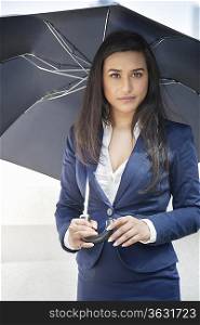 Portrait of a young Indian businesswoman holding umbrella
