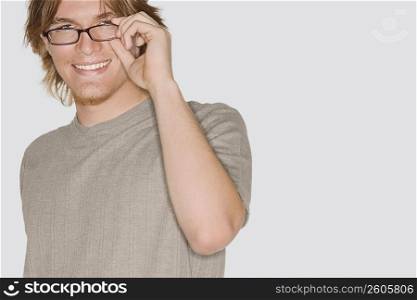 Portrait of a young man adjusting his eyeglasses and smiling
