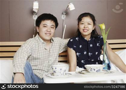 Portrait of a young man and a mid adult woman sitting on the bed