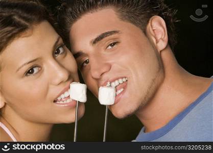Portrait of a young man and a teenage girl eating marshmallows