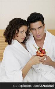 Portrait of a young man and a teenage girl holding a glass of strawberries