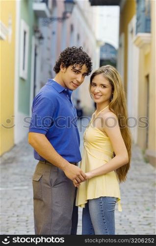 Portrait of a young man and a teenage girl standing on the street and holding hands